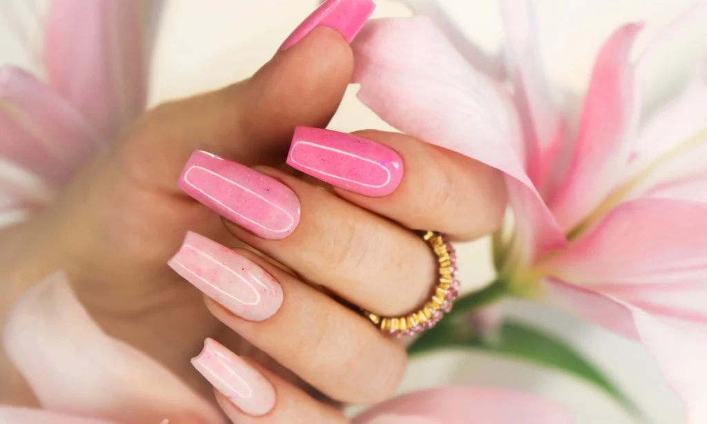 Dłoń z długimi paznokciami w odcieniach różu z połyskiem