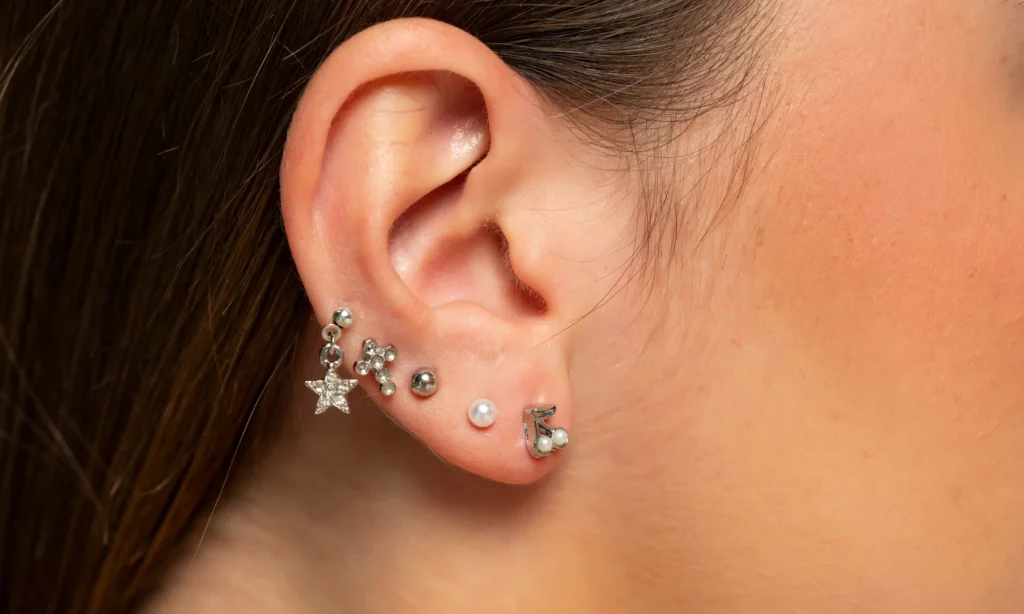 Ucho z kilkoma kolczykami po wykonanym piercingu